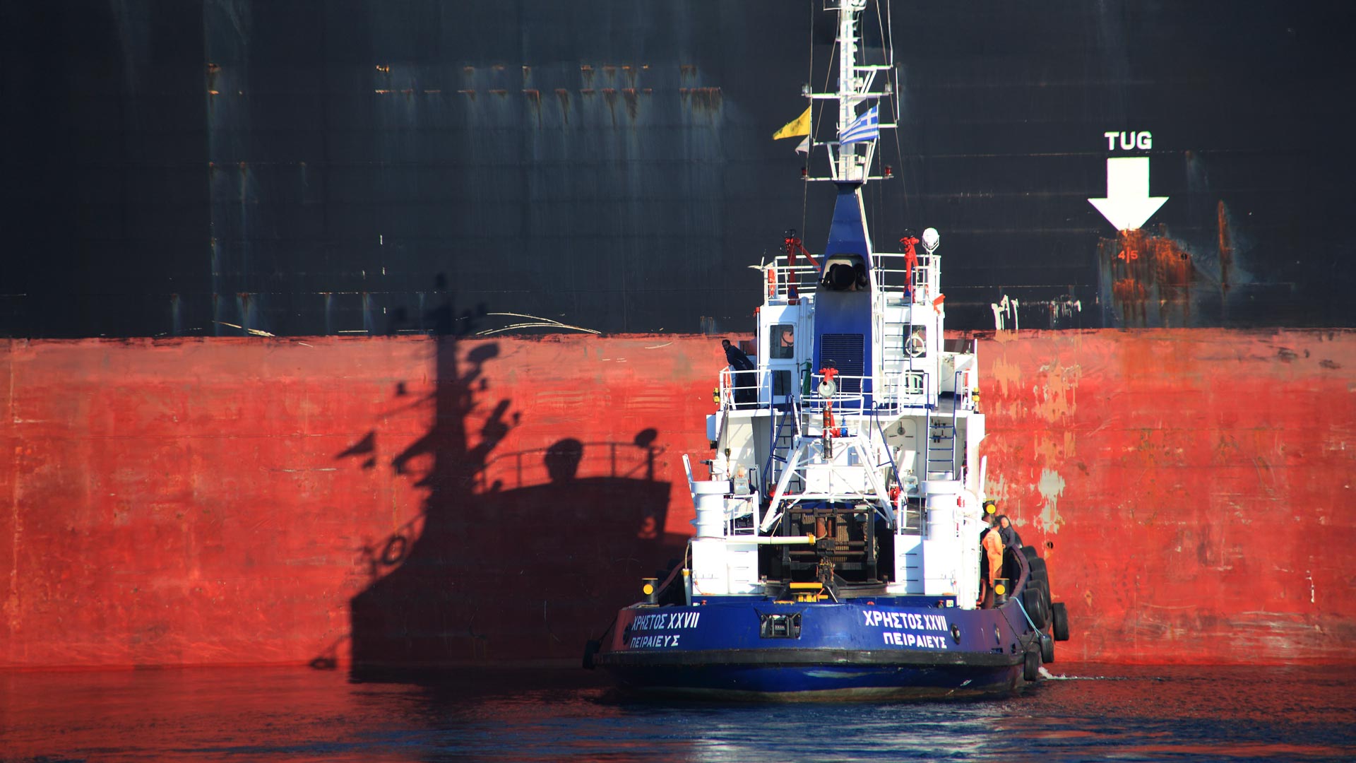 A towage boat right next to a huge cargo boat.